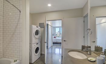 Bathroom with a white tiled shower area and a white washing machine.